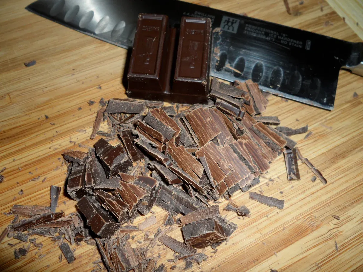 Chocolate being chopped with a knife for truffles, as in a hands-on chocolate workshop in Brussels